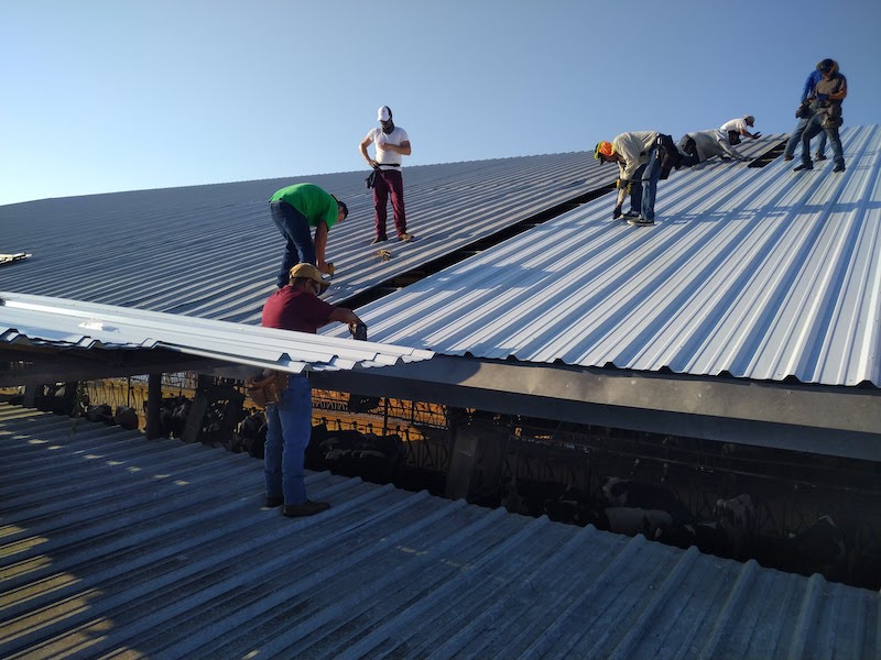 men installing white metal roofing